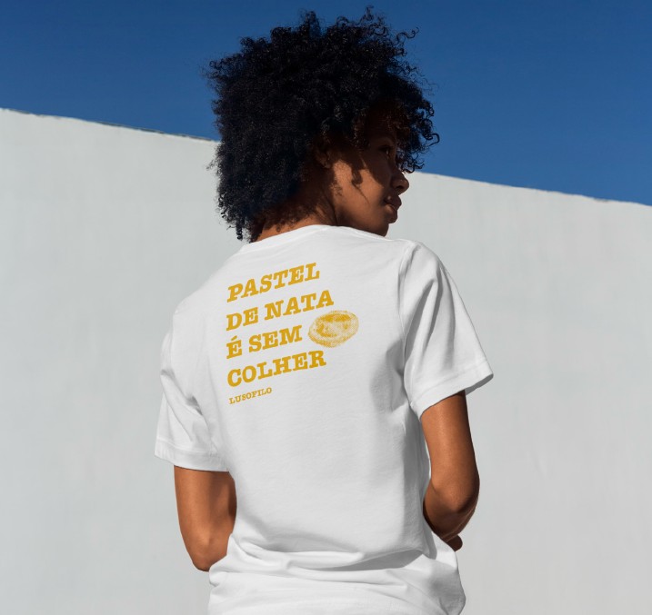 Pessoa de costas com t-shirt branca LusoFilo com a frase Pastel de nata é sem colher